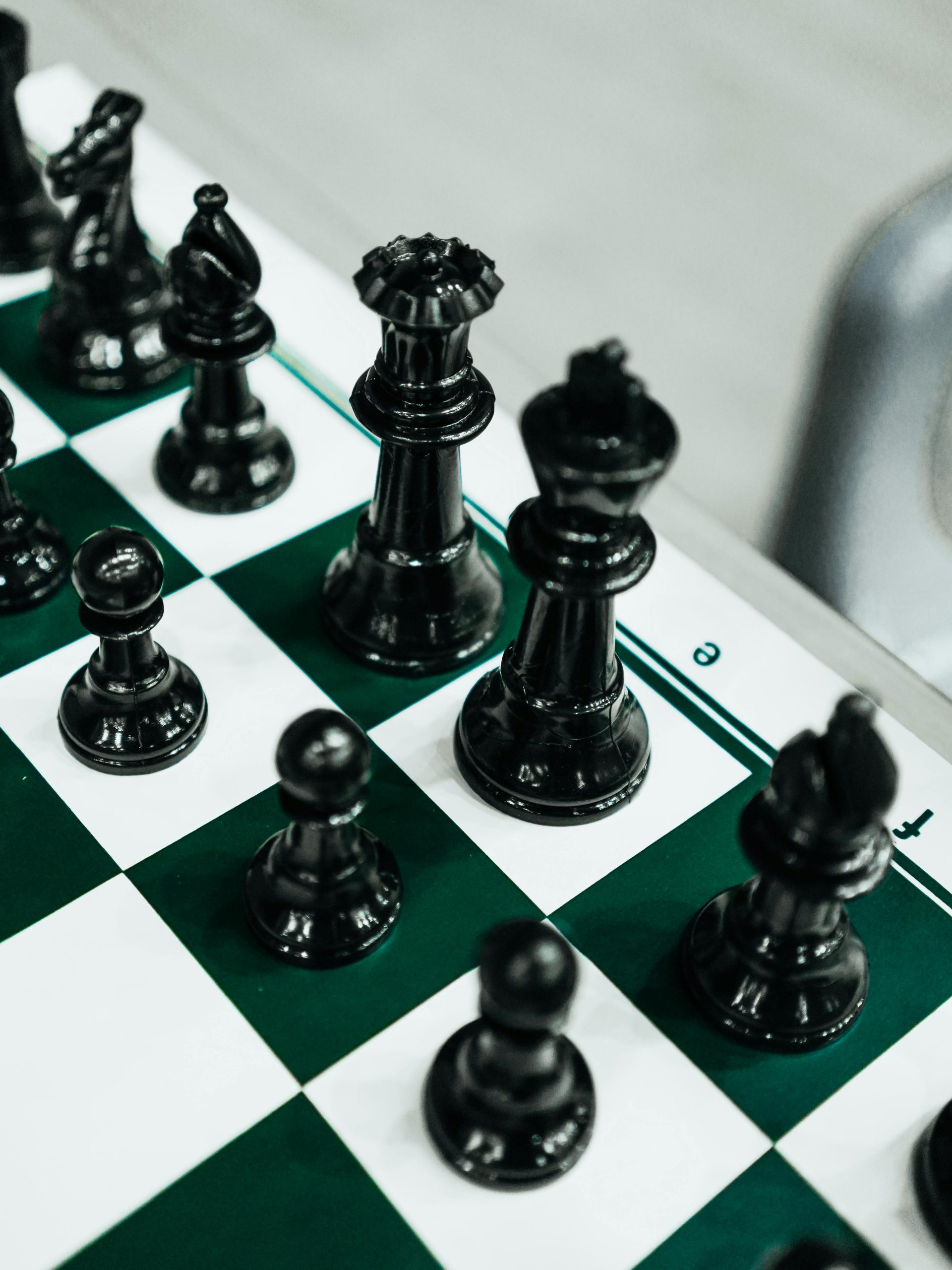 Close-up of elegant black chess pieces on a classic green and white checkered board.