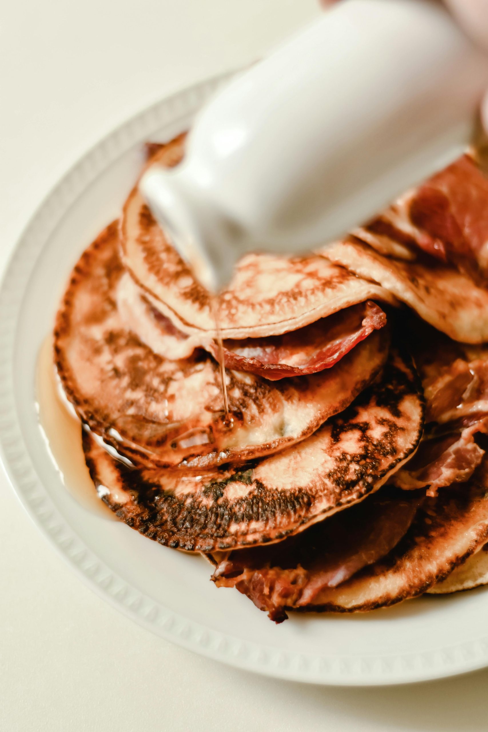 Close-up of fluffy pancakes with maple syrup pouring over them, perfect for breakfast inspiration.